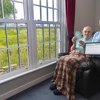 Elain & Bob gyda'r Gwobr Gofalu yn y Gymraeg