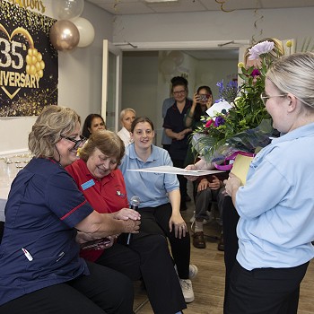 Staff member presenting Meryl with flowers at the 35th celebrations of Cartref Bryn yr Eglwys