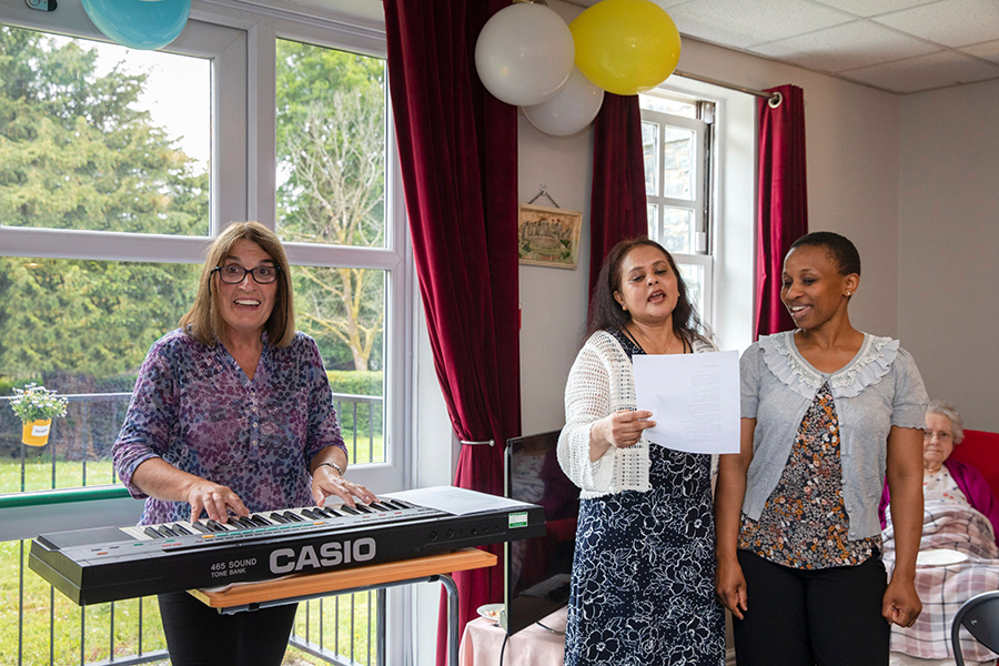 Mererid playing piano with two singers at Cartref Bryn yr Eglwys