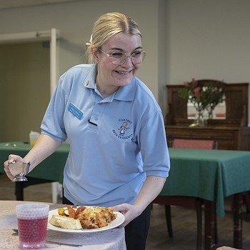 aelod o staff yn gweini plât o fwyd